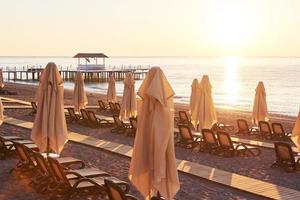 vista panoramica della spiaggia sabbiosa privata con lettini e parasokamy sul mare e sulle montagne. ricorrere. foto