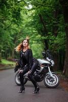 un'attraente ragazza sexy su una moto sportiva in posa all'esterno foto