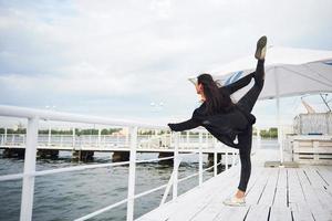 donna sorridente che fa esercizio di yoga all'aperto sul molo della spiaggia foto