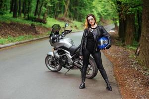 un'attraente ragazza sexy su una moto sportiva in posa all'esterno foto