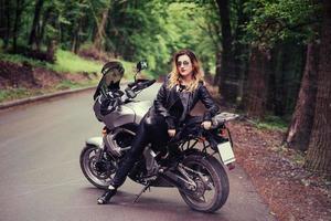 un'attraente ragazza sexy su una moto sportiva in posa all'esterno foto