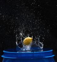 limone giallo che cade nell'acqua blu su sfondo nero foto