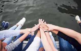 giovani amici seduti sul ponte sul fiume, stile di vita, piedi sull'acqua blu foto