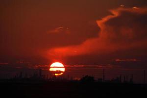 sole che tramonta dietro la raffineria di petrolio regina nel saskatchewan foto