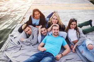 gruppo di bei giovani felici che stanno facendo il villaggio sul molo, i migliori amici di ragazze e ragazzi con la nozione di piacere creano vite emotive foto