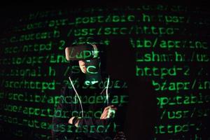 la doppia esposizione di un uomo caucasico e delle cuffie per realtà virtuale è presumibilmente un giocatore o un hacker che decifra il codice in una rete o un server sicuro, con righe di codice foto