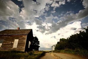 nuvole temporalesche dietro una vecchia fattoria del saskatchewan foto