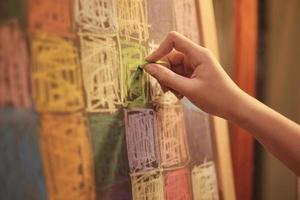 primo piano della creatività della mano della bambina che disegna la pittura artistica alla lavagna nell'educazione per il tempo libero dei bambini con illustrazioni colorate di gesso, rosa, giallo, verde, blu e felicità. foto