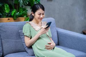 la giovane donna asiatica incinta si rilassa a casa foto