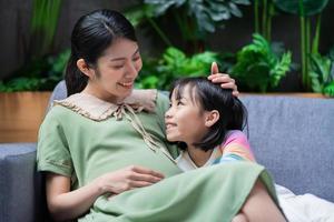 giovane donna asiatica incinta e figlia a casa foto