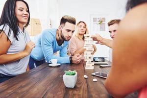 gruppo di amici creativi seduti al tavolo di legno. persone che si divertono mentre giocano a giochi da tavolo foto