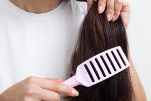 ragazza che si pettina aggrovigliata, fragile, con doppie punte, cura del concetto di capelli lunghi. foto