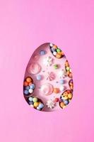 uova di pasqua di cioccolato e decorazioni piatte per bambini concetto di uova di caccia di pasqua su sfondo rosa. dolci a forma di uovo foto