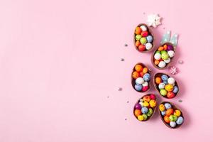 uova di pasqua di cioccolato e decorazioni piatte per bambini concetto di uova di caccia di pasqua su sfondo rosa. dolci a forma di uovo foto