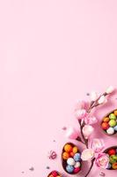 uova di pasqua di cioccolato e decorazioni piatte per bambini concetto di uova di caccia di pasqua su sfondo rosa. dolci a forma di uovo foto
