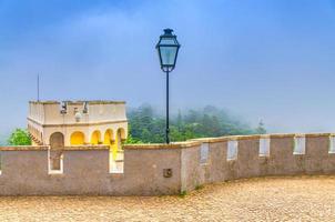 lampada lanterna vintage in ferro e merli sulla torre del castello di palazzo pena, foresta verde nella nebbia, palacio nacional da pena castello romanticista foto