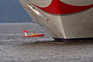 barca a motore che passa la nave da crociera al molo di Prince Rupert foto