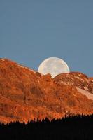 luna piena dietro la montagna nella panoramica alberta foto