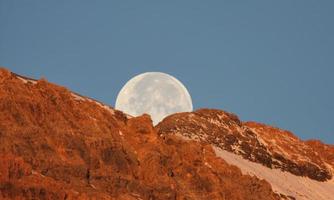 luna piena dietro la montagna nella panoramica alberta foto