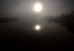 sole riflesso dall'acqua durante una mattinata nebbiosa del saskatchewan foto