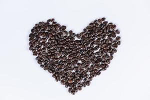 a forma di cuore di chicchi di caffè tostato su sfondo bianco isolato, sapore d'amore e ingredienti per bevande con il concetto di chicchi di caffè tostati. sfondi modello astratto di caffè in grani. foto