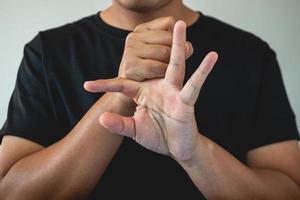 concetto di sindrome dell'ufficio. il dito medio viene massaggiato e allungato dopo il lavoro. Immagine ravvicinata isolare su sfondo blu. vista di diritto. foto