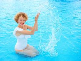 ritratto di donna rossa sorridente che si gode la vita in costume da bagno bianco in piscina foto