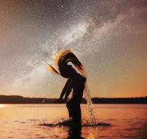 donna sullo sfondo dell'acqua al cielo notturno. fantastico il cielo stellato e la via lattea foto