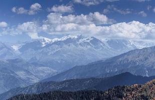 fantastiche montagne innevate nelle bellissime nubi cumuliformi. cresta caucasica principale. tipo mount ushba meyer, georgia foto