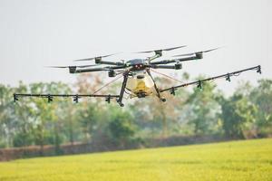 drone agricolo che sorvola il campo di riso per spruzzare prodotti chimici o fertilizzanti. tecnologia per il concetto di agricoltura foto