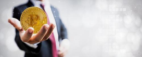 criptovaluta bitcoin, moneta d'oro a disposizione dell'uomo d'affari e uno sfondo grafico sfocato foto