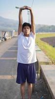 giovane uomo asiatico che si allunga prima di fare jogging al mattino foto