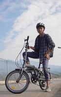 giovane asiatico con lo zaino che riposa dopo il giro in bicicletta foto