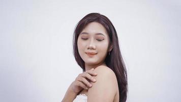 ragazza asiatica con trucco sorridente dolcemente mano spalla laterale isolata su sfondo bianco foto