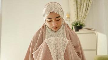 donna musulmana che prega e prega indossando un mukenah foto