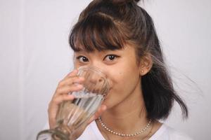 donna asiatica che beve bicchiere d'acqua su sfondo bianco isolato foto