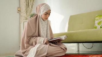 donna musulmana che legge seriamente il Corano a casa foto