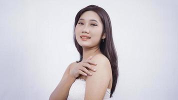 ragazza asiatica con trucco sorridente dolcemente mano spalla laterale isolata su sfondo bianco foto