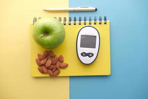 strumenti di misurazione per diabetici, mandorle, mela su sfondo colorato foto