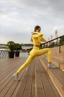 giovane donna che fa esercizio di stretching sul molo lungo il fiume foto