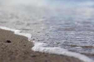 onda splash mare spiaggia macro, primo piano, primo piano di schiuma marina e sabbia bagnata. foto