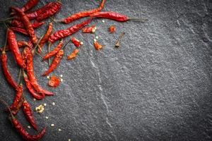 peperoncino essiccato su sfondo scuro - peperoncino rosso di Cayenna essiccato su una pietra foto