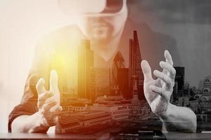 uomo d'affari che indossa occhiali per realtà virtuale in un ufficio moderno con telefono cellulare utilizzando con auricolare vr con esposizione alla città di Londra foto