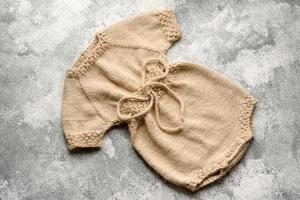 vestiti beige lavorati a maglia per bambini su uno sfondo di cemento bianco foto