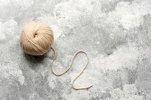 un groviglio di fili di lana color beige su fondo di cemento bianco foto