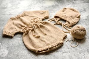 vestiti beige lavorati a maglia per bambini su uno sfondo di cemento bianco foto