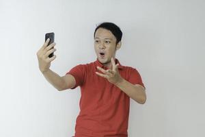 wow il viso del giovane asiatico ha scioccato ciò che vede nello smartphone su sfondo grigio isolato. foto
