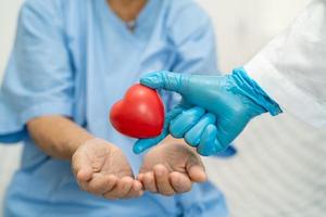 il medico dà il cuore rosso a una donna anziana o anziana asiatica paziente, sano concetto medico foto