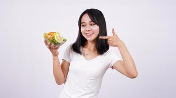 donne asiatiche che puntano il dito su una ciotola di insalata di verdure miste fresche con sfondo bianco isolato foto
