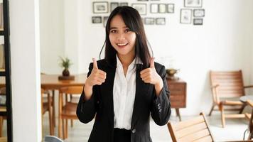 bella giovane donna asiatica d'affari in giacca e cravatta e dito ok alza le mani in ufficio foto